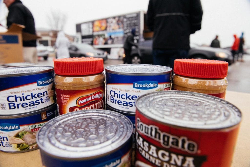 Canned goods and peanut butter are ready to be bagged at a rainy mobile food pantry distribution.