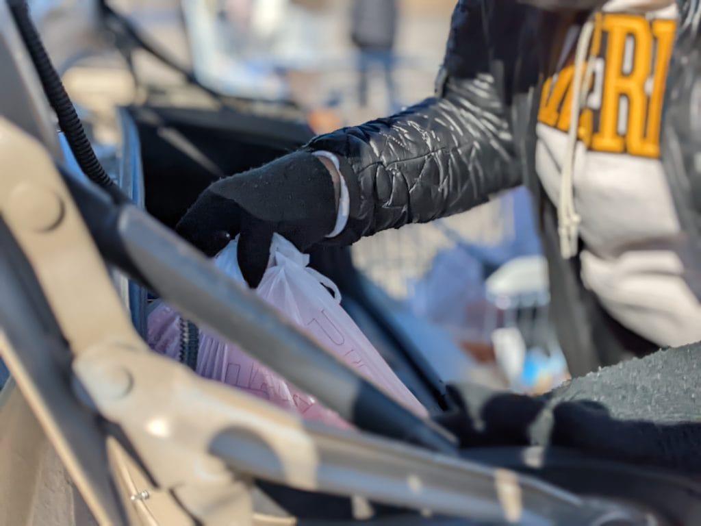 A volunteer loads a car with free food from One Generation Away's mobile food pantry