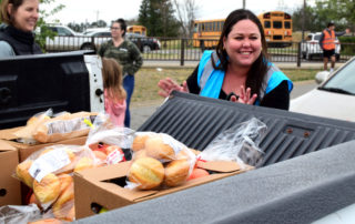 A One Generation Away volunteer loads up a pickup truck with food at a mobile food pantry distribution.