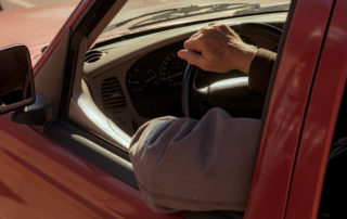 A man drives through OneGenAway's mobile food pantry in a red truck to receive food.
