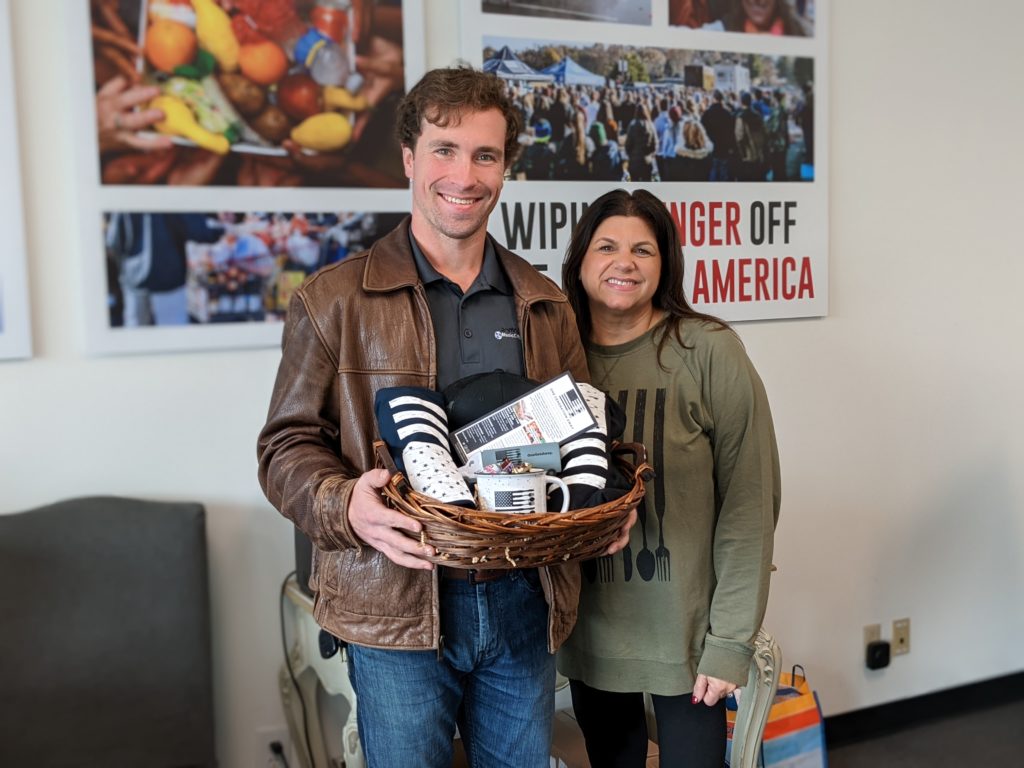 OneGenAway founder and director of development Elaine Whitney stands with volunteer Timothy Myles, who is holding a gift basket of OneGenAway swag