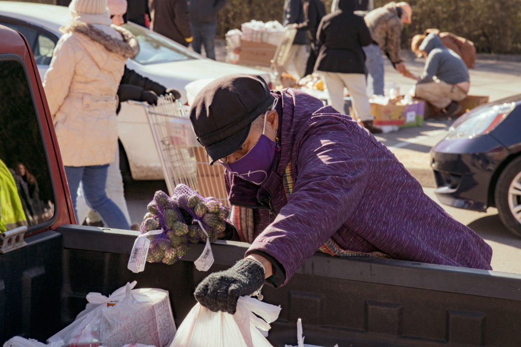 Laura fills the back of a truck with groceries at a OneGenAway mobile food pantry distribution.