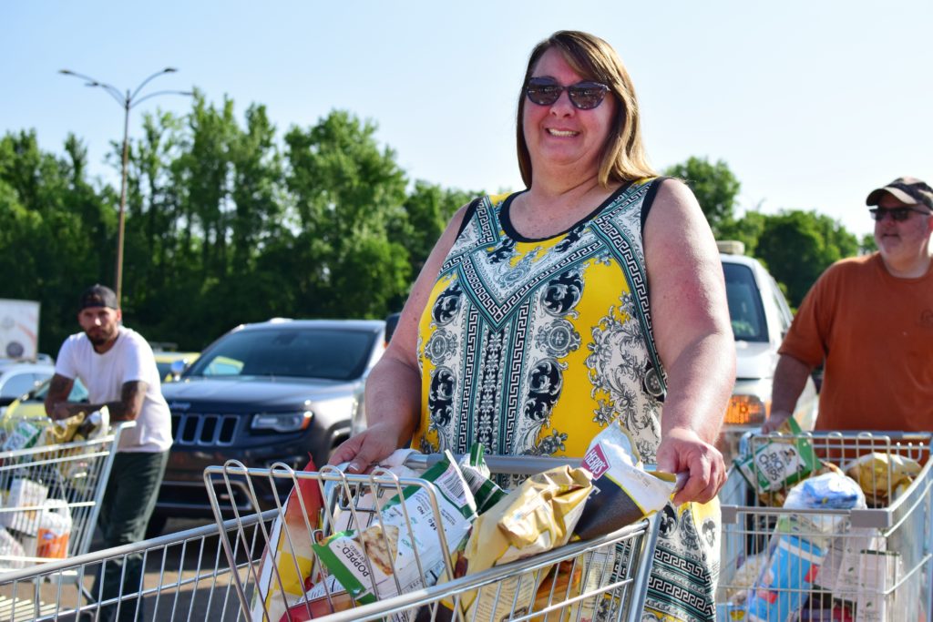 Becky pushes a cart full of food at OneGenAway's mobile food pantry.