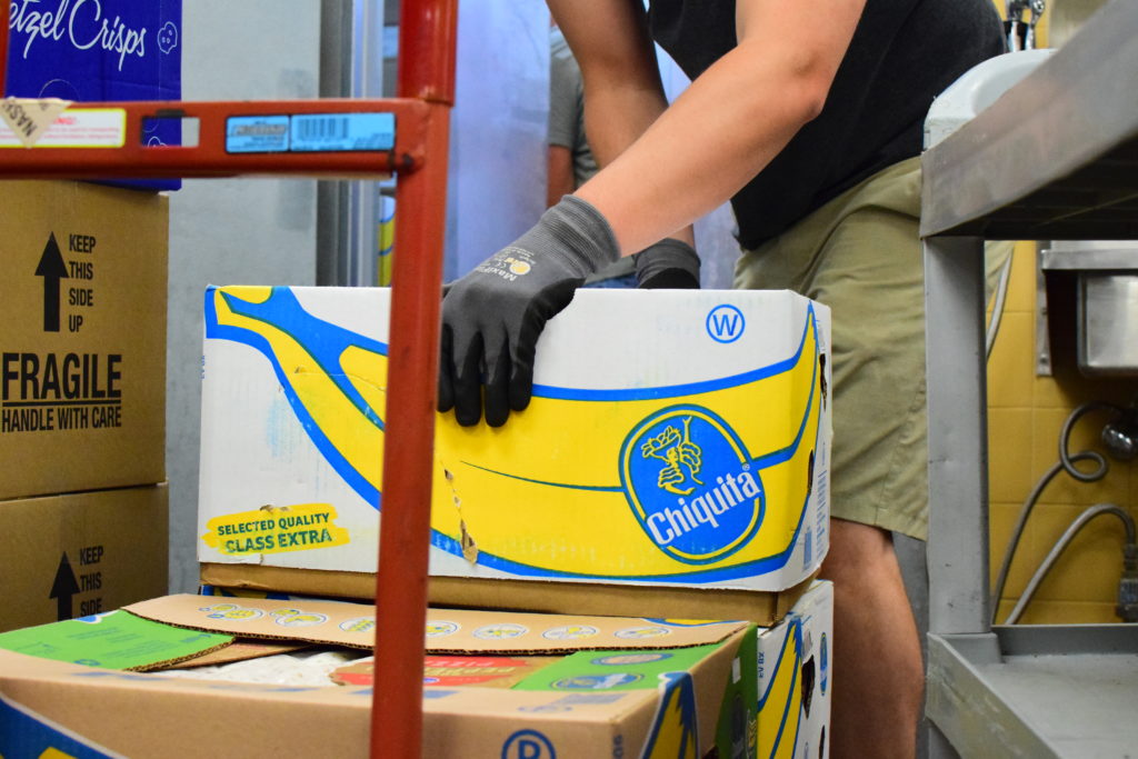 A OneGenAway First Responder places rescued food on a dolly to wheel it out of the store and into OneGenAway's refrigerated truck.