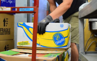 A OneGenAway First Responder places rescued food on a dolly to wheel it out of the store and into OneGenAway's refrigerated truck.