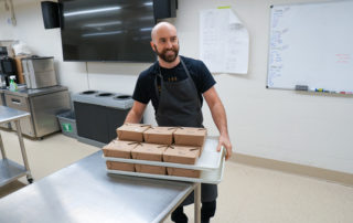 Ben Tyson carries boxed restaurant-inspired meals to the Patchwork fridge.