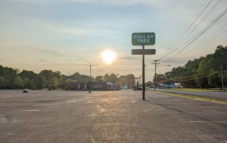The sun rises behind a Dollar Tree sign in an empty parking lot in Waverly Tennessee